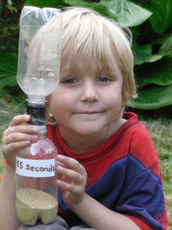 Young boy holding home-made sand timer Young boy holding home-made sand timer